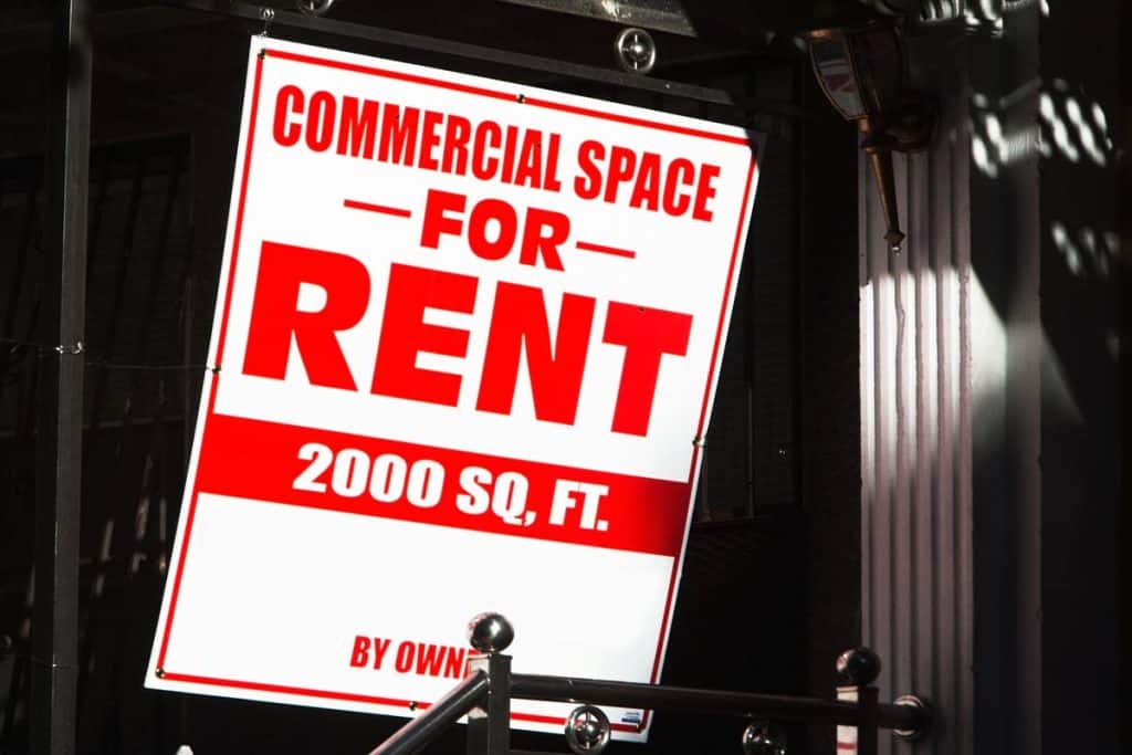 A red and white sign reading "COMMERCIAL SPACE FOR RENT" posted on a building in NYC